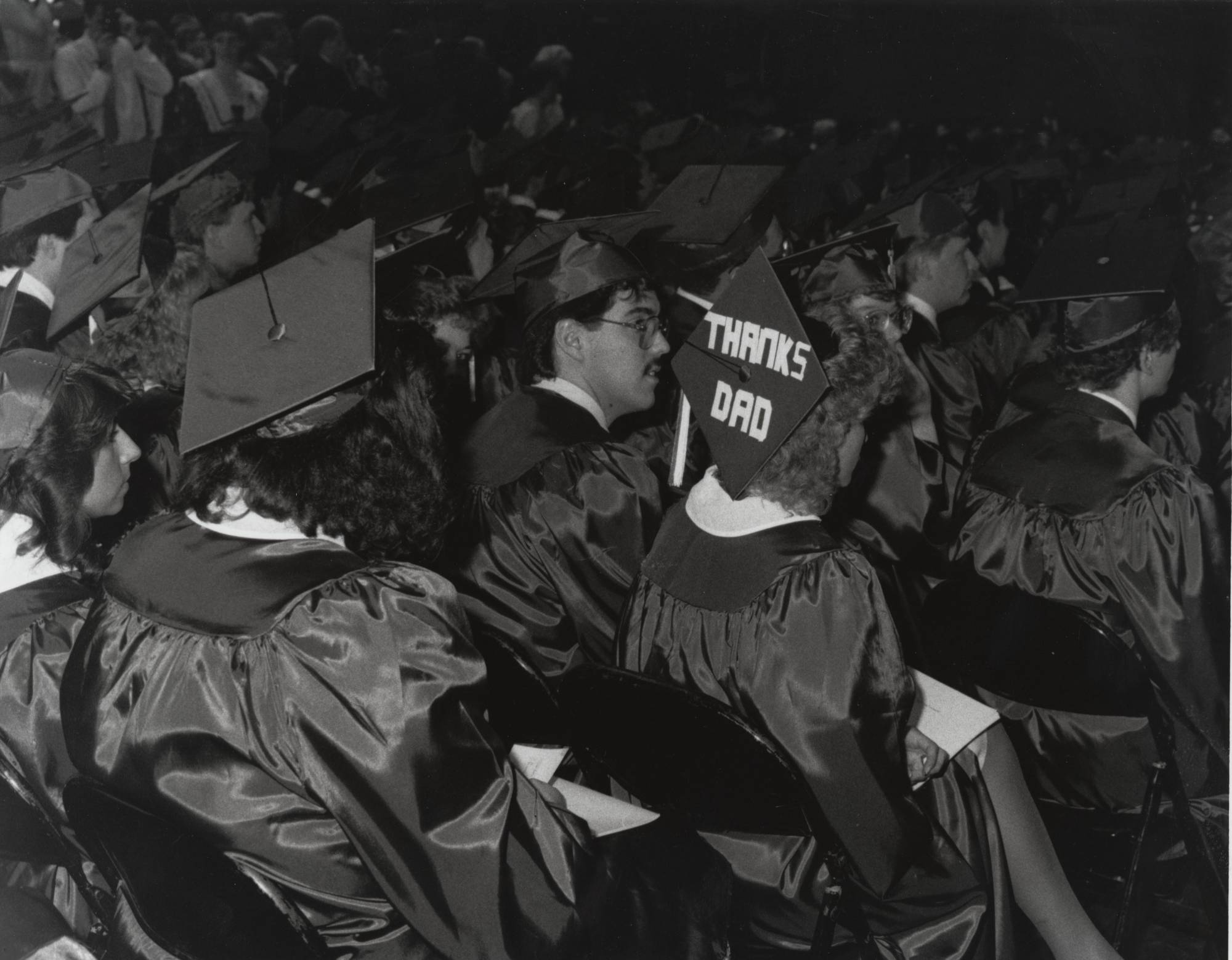 Group of students at the 1988 commencement ceremony. One student's cap reads, "Thanks Dad", 1988.